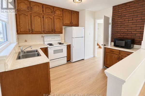 Kitchen with light wood cabinets, white appliances, a double sink, and cream-colored countertops. - 223 Ellendale Drive, Toronto