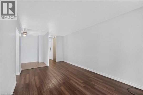 Open concept living space with dark wood flooring and a glimpse of the kitchen. - 223 Jackson Street W Unit# 908, Hamilton
