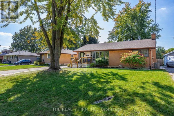 Wide shot of the bungalow from the front lawn, showing the driveway and trees. - 223 Michaelmas Street, London East