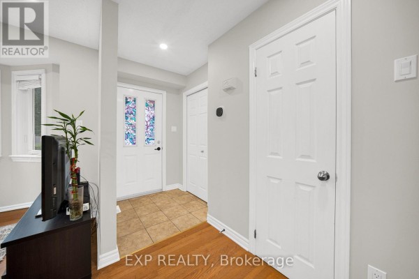 Foyer with beige tiled floor, wood floors, white doors, and stained glass panels. - 223 Monterey Drive, Ottawa