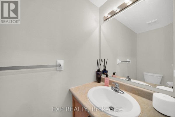 Powder room with a light grey vanity, beige countertop, white sink, and large mirror. - 223 Monterey Drive, Ottawa