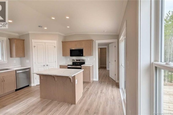 Kitchen with light wood cabinetry, a granite-top island, stainless steel appliances, and laminate flooring. - 223 Rue Bella Vista, Tracadie