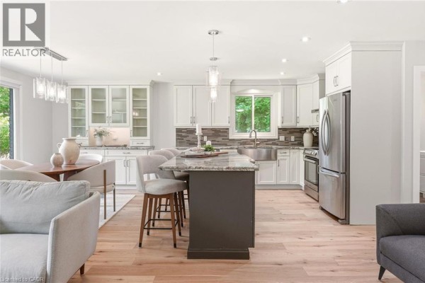 Open-concept kitchen and dining area with white cabinets, granite countertops, and a large island with seating. - 2234 Kilbride Street, Burlington