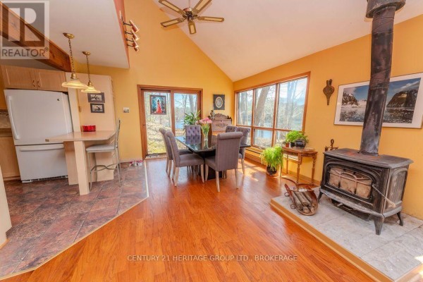 Living room with wood stove, dining area, and kitchen breakfast bar - 2238 Little Long Lake Road Frontenac