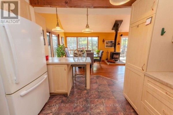 Kitchen with white refrigerator, wood cabinets, and wood stove - 2238 Little Long Lake Road Frontenac