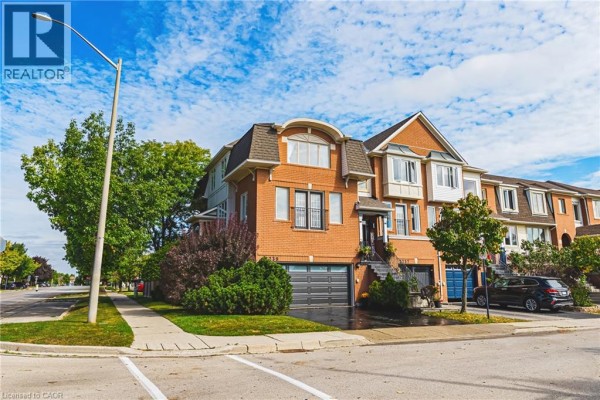 Exterior view of the brick townhouse with lush greenery and a clear blue sky. - 2239 Prescott Place, Burlington