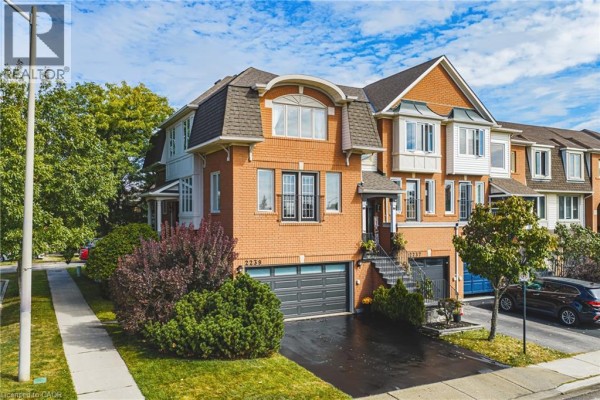 Facade of a three-story brick townhouse featuring multiple windows and a dark shingle mansard roof. - 2239 Prescott Place, Burlington