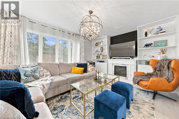 Living room with a large sectional sofa, fireplace, built-in shelves, and an ornate chandelier. - 2239 Prescott Place, Burlington