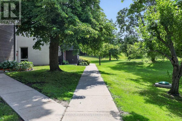 Concrete walkway through grassy area with mature trees in a residential setting. - 224 - 1102 Horseshoe Valley Road W, Oro Medonte