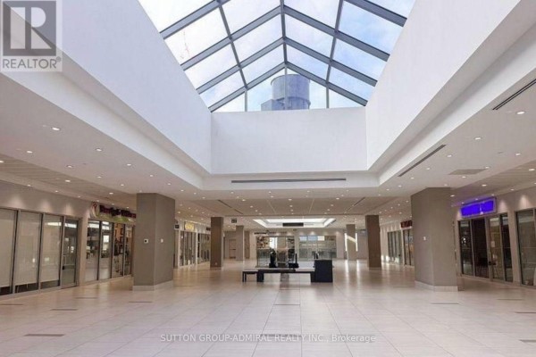 Interior of a shopping mall with a glass skylight, storefronts, and seating areas. - 224 - 7777 Weston Road, Vaughan