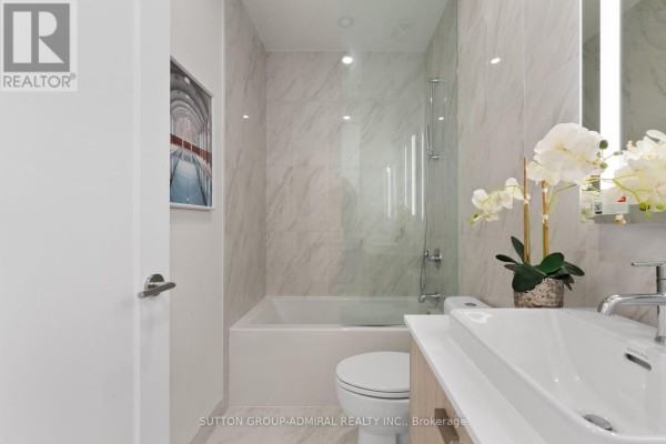 Bathroom with a bathtub, toilet, vanity, and marble tile accents. - 224 - 858 Dupont Street, Toronto
