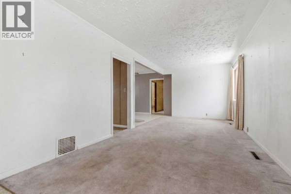 Empty living room with beige carpet and light-colored walls. - 224 1 Street S, Vulcan