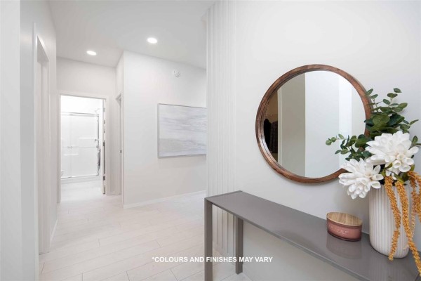 Entryway looking down a hallway with white walls, tiled floor, and a round mirror on the wall. - 224 Blossom Way, West St Paul