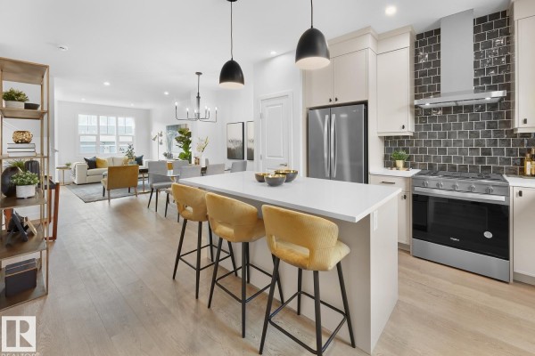 View of kitchen, dining area, and living room with light wood floors. - 224 Chappelle Dr Sw, Edmonton