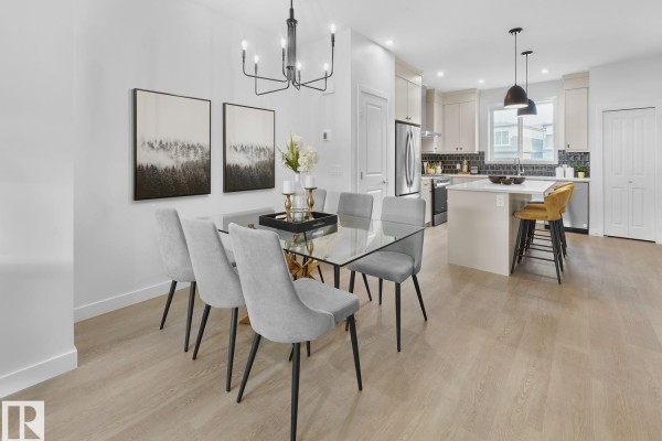 Dining area with glass table, upholstered chairs, and view of kitchen. - 224 Chappelle Dr Sw, Edmonton