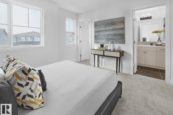 Bedroom with king-size bed, two windows, and ensuite bathroom entrance. - 224 Chappelle Dr Sw, Edmonton