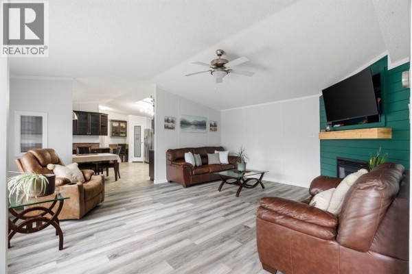 Close-up view of a wooden deck and pergola attached to a beige mobile home in a backyard. - 224 Clausen Crescent, Fort Mcmurray