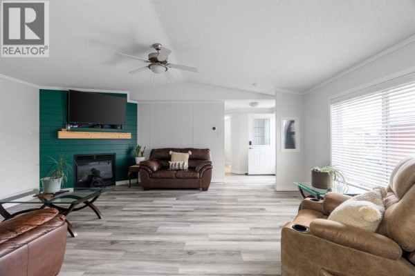Wooden deck with lattice skirting and railing on the exterior of a beige mobile home. - 224 Clausen Crescent, Fort Mcmurray
