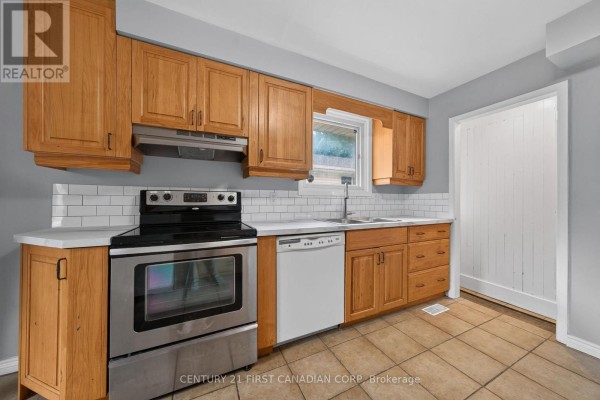 Kitchen counter with stainless steel stove, dishwasher, white subway tile backsplash, and oak cabinets. - 224 Culver Crescent, London East