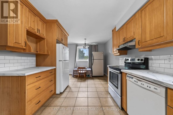 Kitchen with two refrigerators, oak cabinets, stainless steel stove, dishwasher, and tiled floor. - 224 Culver Crescent, London East
