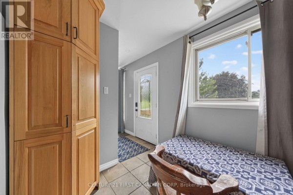 Kitchen area with a large oak cabinet, a window with curtains, and a glass-paneled front door. - 224 Culver Crescent, London East