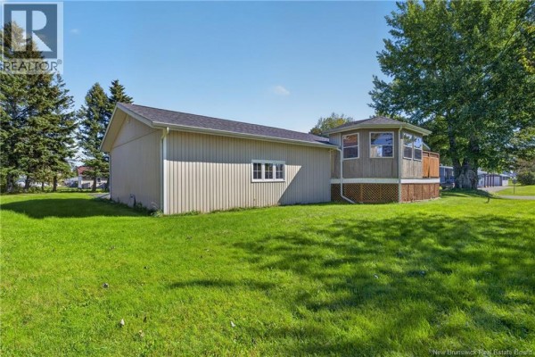 Back exterior of house with beige siding and attached screened sunroom. - 224 Francine, Beresford