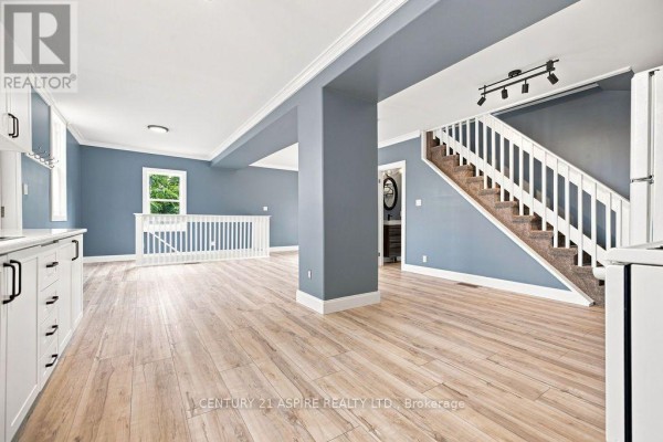 Open concept living area with wood-look floors, stairs and kitchen cabinets - 224 Nelson Street Pembroke