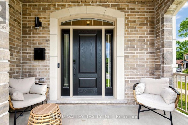 Close-up of a black front door with glass panels, flanked by two chairs on a covered porch. - 224 Severn Street, Oshawa