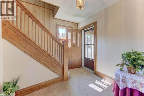 Interior view of a sunroom with brick walls, a wooden bench, patterned carpet, and windows overlooking the street. - 224 Weber Street E, Kitchener