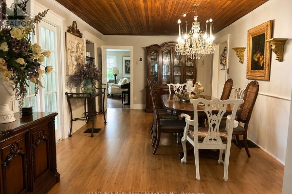 Formal dining room with a chandelier, wooden table set for six, and a china cabinet. - 2241 Four Mile Creek Road, Niagara On The Lake