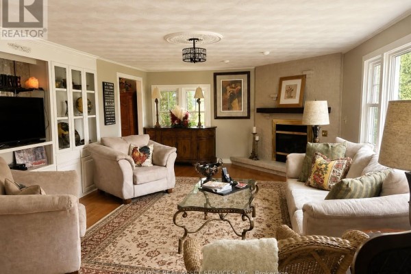Living room with plush furniture, a fireplace, built-in shelving, and a patterned area rug. - 2241 Four Mile Creek Road, Niagara On The Lake
