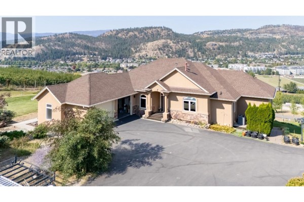 Exterior of a tan stucco house with a multi-level roof and attached garage. - 2241 Rojem Road, Kelowna