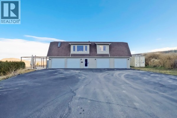 Front exterior of a long barn-like structure with six garage doors. - 2241 Rojem Road, Kelowna
