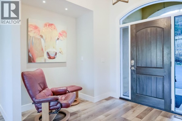 Interior view of a home entrance with a dark wood door and abstract cow art. - 2241 Rojem Road, Kelowna