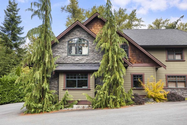 Close-up of the home's facade, showing stonework, siding, and windows. - 22441 79 Avenue, Langley