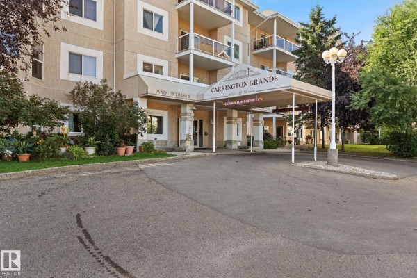 Covered main entrance of Carrington Grande apartment building with landscaping. - #225 10511 42 Av Nw, Edmonton