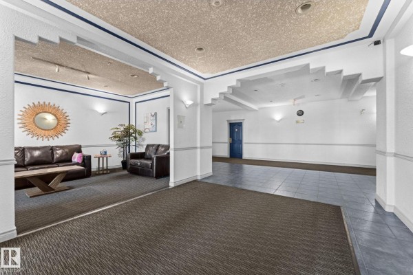 Apartment building lobby seating area with two brown leather sofas and a wooden table. - #225 10511 42 Av Nw, Edmonton