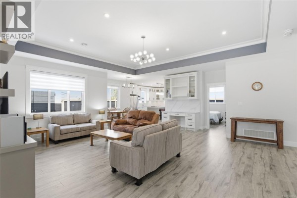 Open concept living area with sofas, dining table, kitchen island, and desk. - 225 Dunbar Way, Parksville