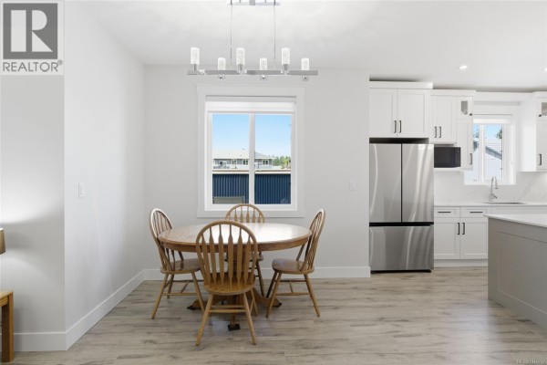 Dining area with round wooden table, chairs, and stainless steel refrigerator. - 225 Dunbar Way, Parksville