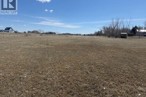 Distant view of buildings and vehicles across a large, open, grassy field. - 225 Gordon Drive, Mckillop Rm No  220