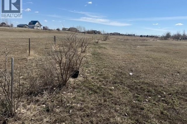 Distant view of buildings and vehicles across a large, open, grassy field. - 225 Gordon Drive, Mckillop Rm No  220