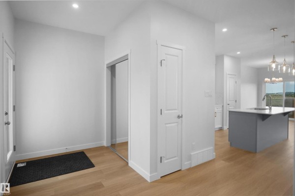 Living room with large window, light fixtures, and access to the staircase - 2250 194a St Nw, Edmonton