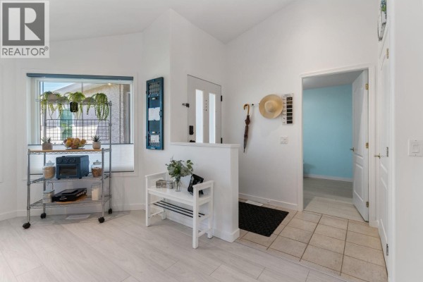 Bright entryway with white bench, tiled floor, and view into blue painted room. - 2250 Louie Drive Unit# 85, Westbank