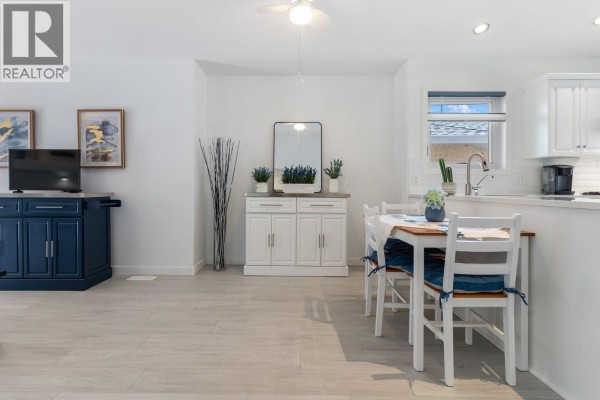 Dining area with white chairs and table adjacent to kitchen, overlooking living space. - 2250 Louie Drive Unit# 85, Westbank