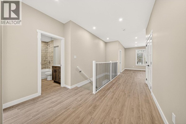 Front exterior of a beige house with stone accents, a double garage door, and a white sedan parked in the driveway. - 2252 Black Hawk Drive, Sparwood
