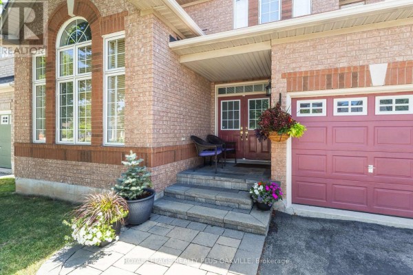 Close-up of the front entrance with stone steps, double doors, potted plants, and a garage. - 2254 Dunforest Crescent, Oakville