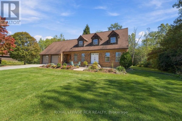 Front exterior of a brick house with a covered porch and large grassy yard. - 22541 Kennedy Road, East Gwillimbury