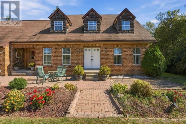 Close-up of the front entrance with double doors, brick walkway, patio seating, and flower beds. - 22541 Kennedy Road, East Gwillimbury