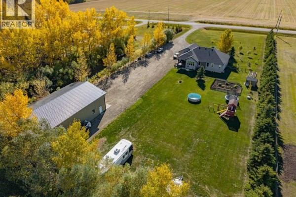 Aerial view of the property showing the house, detached garage, backyard amenities, and surrounding fields. - 2256 Township Road 334, Rural Mountain View County