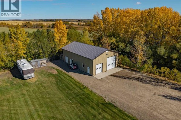 Exterior view of a large detached garage with two bay doors and an RV parked nearby. - 2256 Township Road 334, Rural Mountain View County